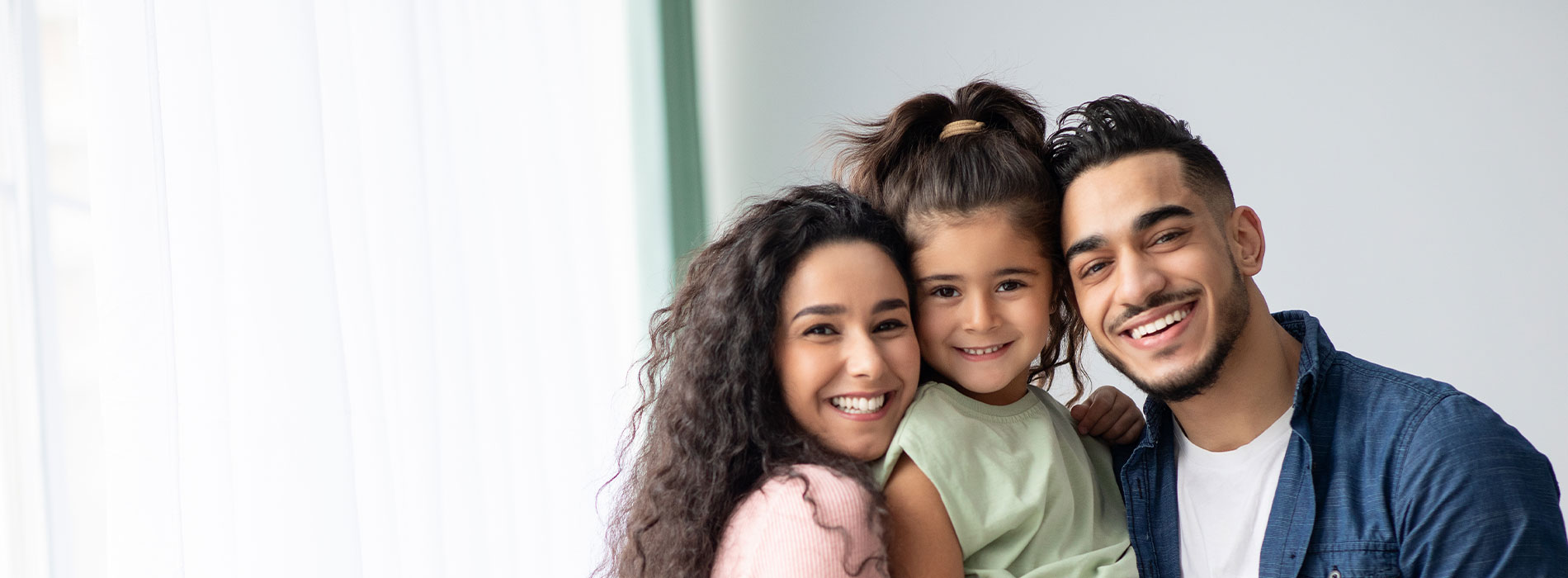 The image is a photograph of a family, featuring an adult male and two young children, smiling and posing together.