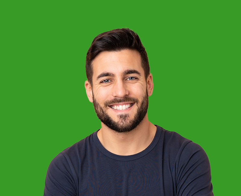 The image features a man with facial hair, smiling at the camera. He is wearing a dark top and has short hair. The background is plain purple.